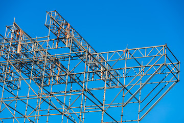 Metallic structure of assembled pipes to hold a stage, blue sky background.