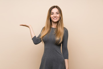 Young woman over isolated background holding copyspace imaginary on the palm to insert an ad