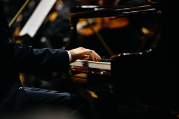 Pianist playing a piece on a grand piano at a concert, seen from the side. - obrazy, fototapety, plakaty