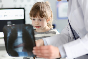 Cute little girl talking with gp looking at xray picture during consultation
