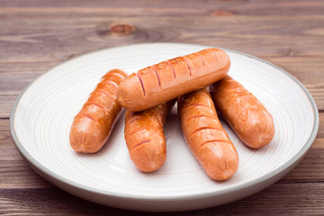 Grilled chicken sausages ready to eat on a plate on a wooden table