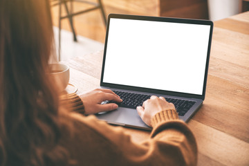 Mockup image of a woman using and typing on laptop computer keyboard with blank white desktop screen with coffee cup on wooden table - obrazy, fototapety, plakaty