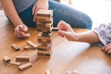 Group of friends sitting and playing Tumble tower wooden block game together with feeling happy