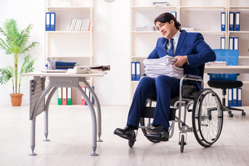 Young male employee in wheelchair working in the office 