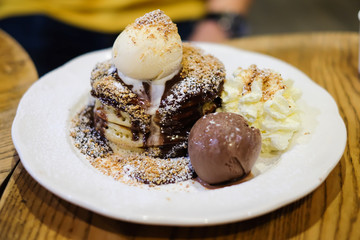 Pancake with almond, whipped cream, honey and vanilla ice cream serve on white dish for dessert background or texture.