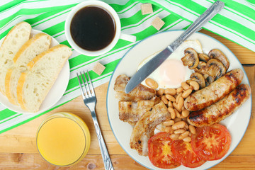Classic English breakfast served: eggs, bacon, beans, juice and tea