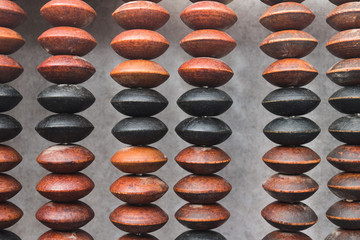 Close up on a retro wooden abacus. Outdated financial equipment. Brown and black bids of a counting...