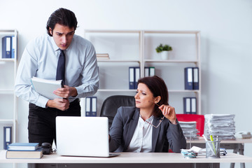 Old female boss and young male employee in the office  