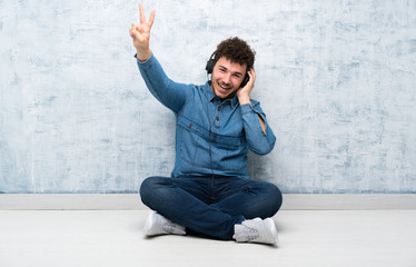 Young man sitting on the floor listening to music with headphones