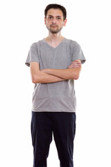 Studio shot of young man standing with arms crossed