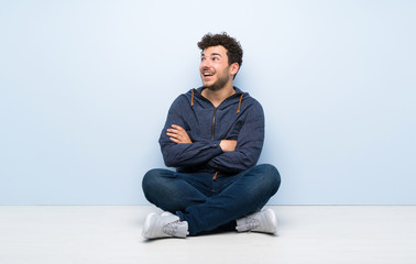 Young man sitting on the floor happy and smiling