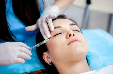 Obraz na płótnie Canvas Cosmetology clinic, cosmetologist doctor with a filler syringe for injection on the face. wrinkle treatment and facial contour correction. face plan