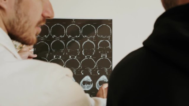 Medical Scientist or surgeon Discussing CT MRI Brain Scan Images, explaining brain damage or cnacer to patient or intern. Neurologists Neuroscientists in Neurological Research Center,talk to client