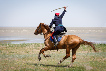 Don Cossack fast rides along the seashore on a horse with a sabre in his hand