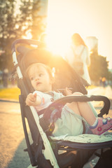 Restless little girl in baby carriage curious looking around