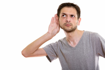Studio shot of young man listening while thinking and looking up