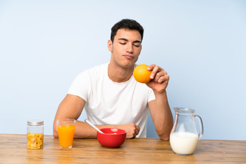 Handsome man in having breakfast and holding an orange