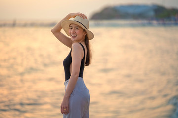 relaxing time concept with portrait traveler girl posing smile in the sea beach in beautiful sunset time