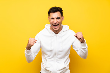 Lucky handsome man over isolated yellow wall