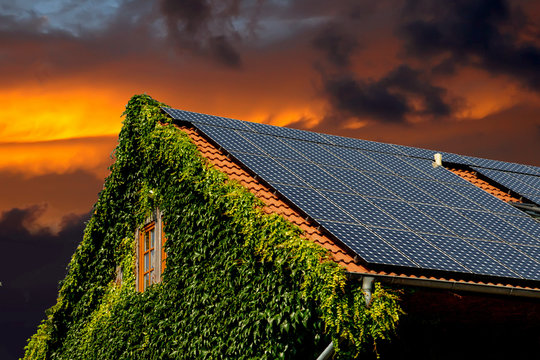 Hausdach mit Solarplatten bei Sonnenaufgang