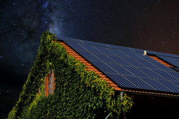 Hausdach mit Solarplatten vor Nachthimmel