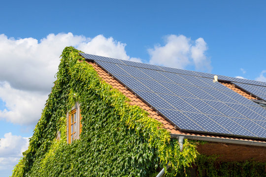 Hausdach mit Solarplatten vor blauem Himmel