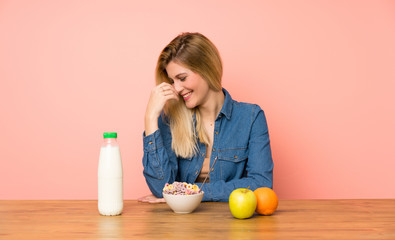 Young blonde woman with bowl of cereals laughing