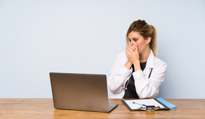 Blonde doctor woman covering mouth and looking to the side