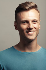 Fototapeta premium Fabulous at any age. Portrait of handsome 30-year-old man with blue eyes standing over gray background. Close up. Classic style. Shiny white smile. Headshot. Studio shot