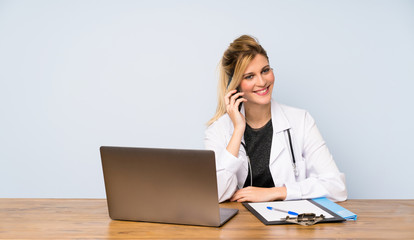 Blonde doctor woman keeping a conversation with the mobile phone