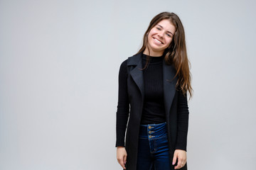 Photo portrait of a beautiful smiling brunette business woman on a white background in a black business suit with long beautiful dark hair in the studio.