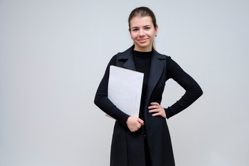 Photo portrait of a beautiful smiling brunette business woman with a folder on a white background in a black business suit with long beautiful dark hair in the studio.