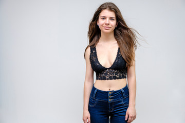 Photo portrait of a beautiful smiling brunette woman girl on a white background in jeans and a blouse with long beautiful flowing dark hair in the studio.