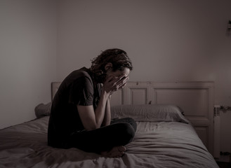 Fototapeta premium Desperate lonely teenager man suffering from depression sitting alone on bed