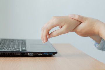 Female arms holding her painful wrist caused by prolonged work on the computer, laptop.Carpal tunnel syndrome, arthritis,healthcare concept.