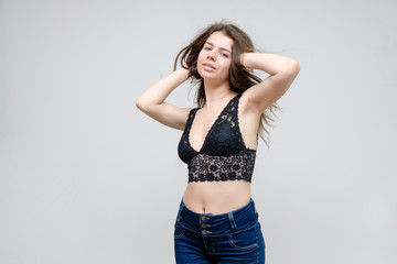 Fototapeta premium Photo portrait of a beautiful smiling brunette woman girl on a white background in jeans and a blouse with long beautiful flowing dark hair in the studio.