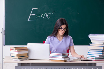 Young female teacher student in front of green board 