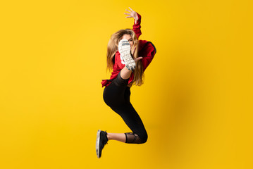 Urban Ballerina dancing over isolated yellow background and jumping