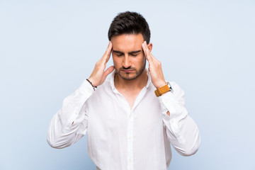 Handsome young man over isolated blue background with headache