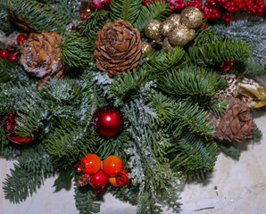 Christmas composition of pine branches, golden Christmas decorations, red berries and artificial snow.