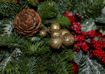 Christmas composition of pine branches, golden Christmas decorations, red berries and artificial snow.