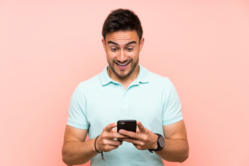 Handsome young man over isolated background surprised and sending a message