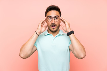 Handsome young man over isolated background with glasses and surprised