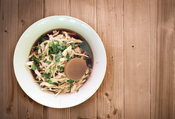 Chicken noodel with hot soup with herb on wood table