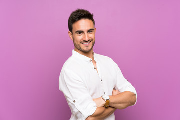 Handsome young man over isolated background with arms crossed and looking forward