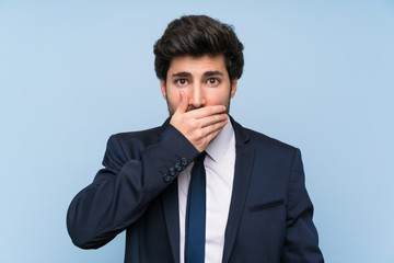 Businessman over isolated blue wall covering mouth with hands