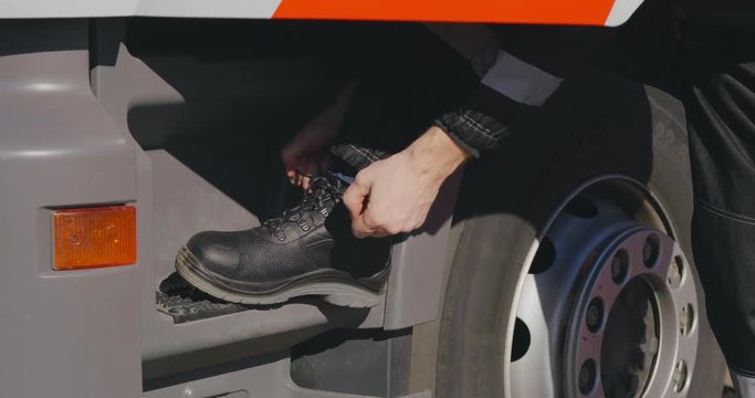 Oil worker prepares for working day and ties shoe laces