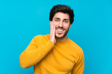 Handsome over isolated blue wall with surprise and shocked facial expression