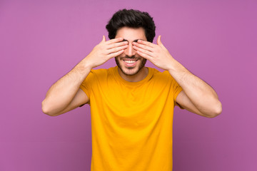 Handsome over isolated purple wall covering eyes by hands