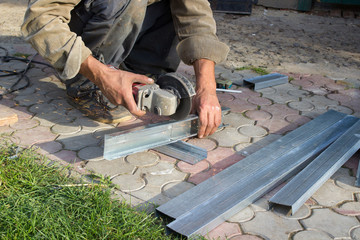 cuting metal profile for drywall,A man cut Angle grinder a metal profile for drywall, guiding a metal profile